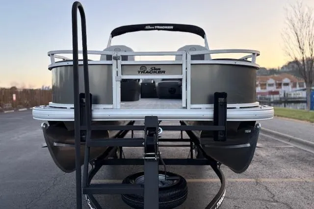 Slide: The Image of 2026 Sun Tracker Bass Buggy 18 DLX pontoon boat on trailer, rear view at sunset. - 11
