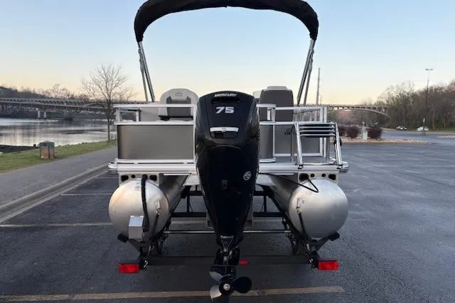 Slide: The Image of 2026 Sun Tracker Bass Buggy 18 DLX pontoon boat with Mercury 75 engine, parked near a river. - 12