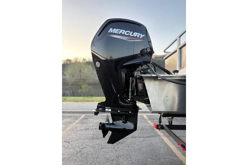 Slide: The Image of 2026 Sun Tracker Bass Buggy 18 DLX with Mercury outboard motor in a parking lot. - 23