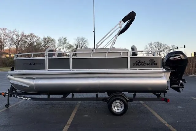 Slide: The Image of 2026 Sun Tracker Bass Buggy 18 DLX pontoon boat on trailer in parking lot. - 6