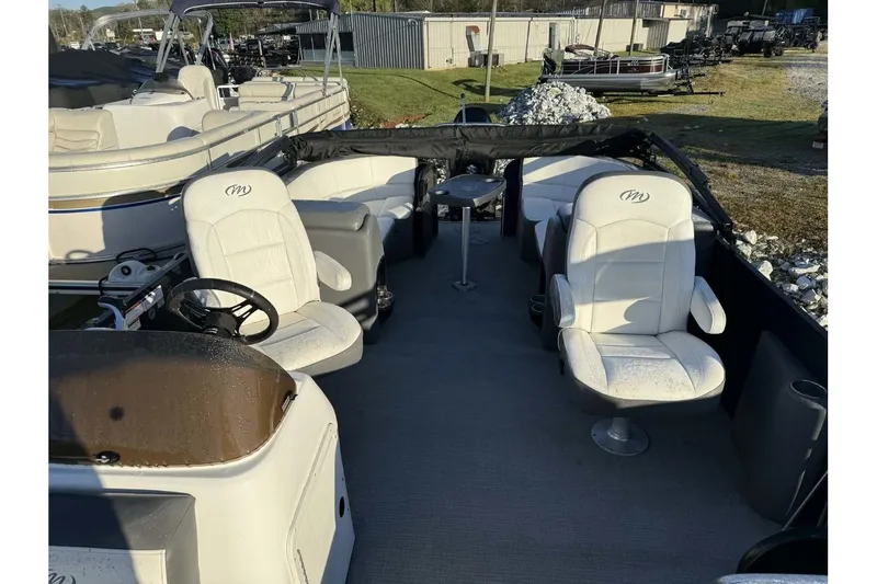 Slide: The Image of 2022 Manitou 25 Aurora pontoon boat interior with white seating and steering wheel. - 3
