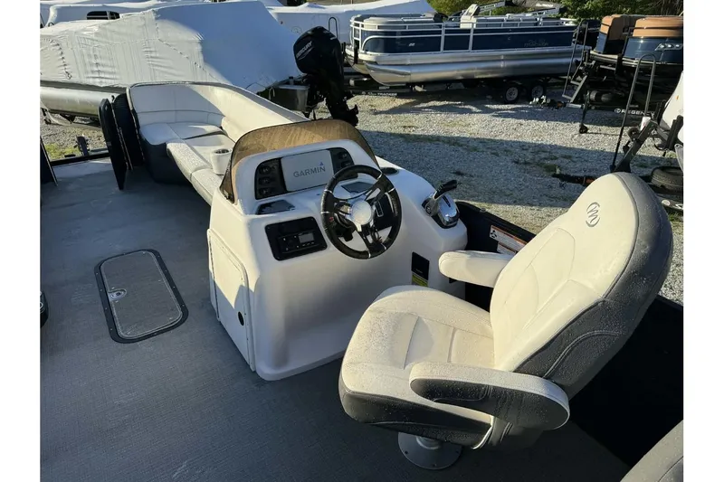 Slide: The Image of 2022 Manitou 25 Aurora boat interior with captain's chair and Garmin navigation system. - 6