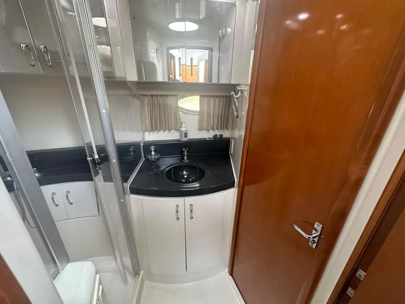 Slide: The Image of 2005 Carver 36 Super Sport yacht bathroom with black countertop and wooden door. - 18