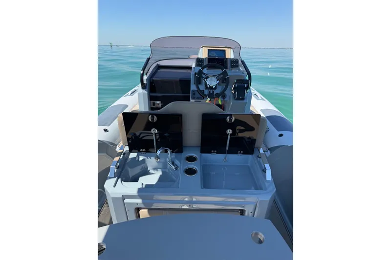 Slide: The Image of 2026 Ranieri Cayman Executive boat interior with steering console and dual sinks on calm water. - 16