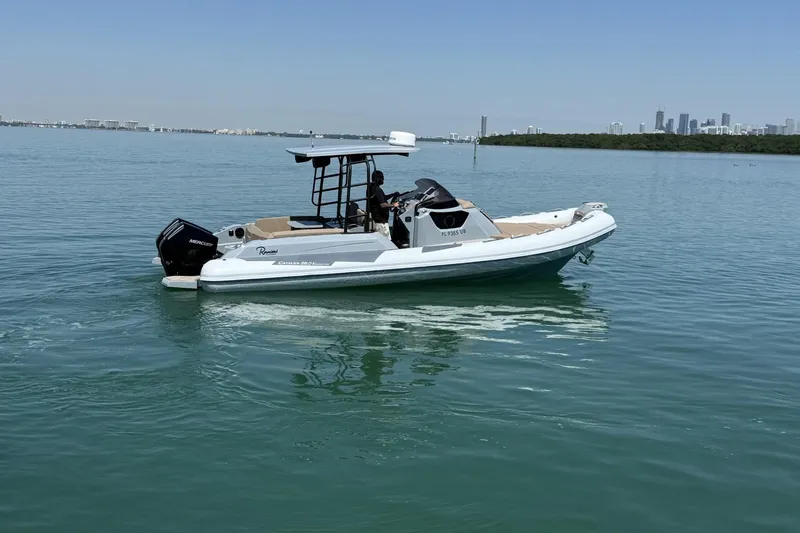 Slide: The Image of 2026 Ranieri Cayman Executive boat cruising on calm waters with city skyline in background. - 8