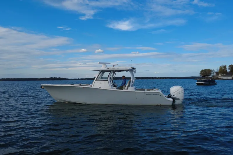The Image of 2022 Sportsman Open 322 Center Console boat cruising on a calm lake under a blue sky. - 0