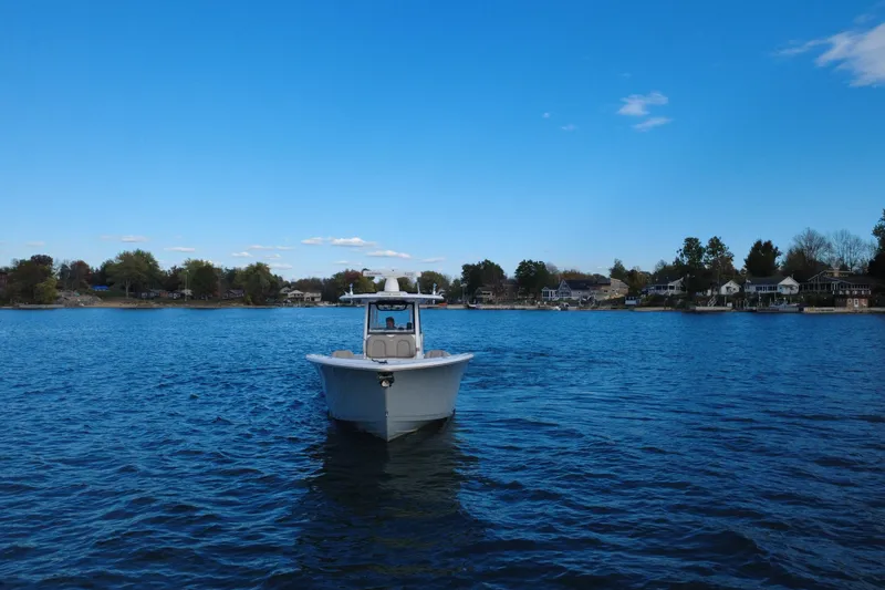 Slide: The Image of 2022 Sportsman Open 322 Center Console boat on a serene lake under a clear blue sky. - 2