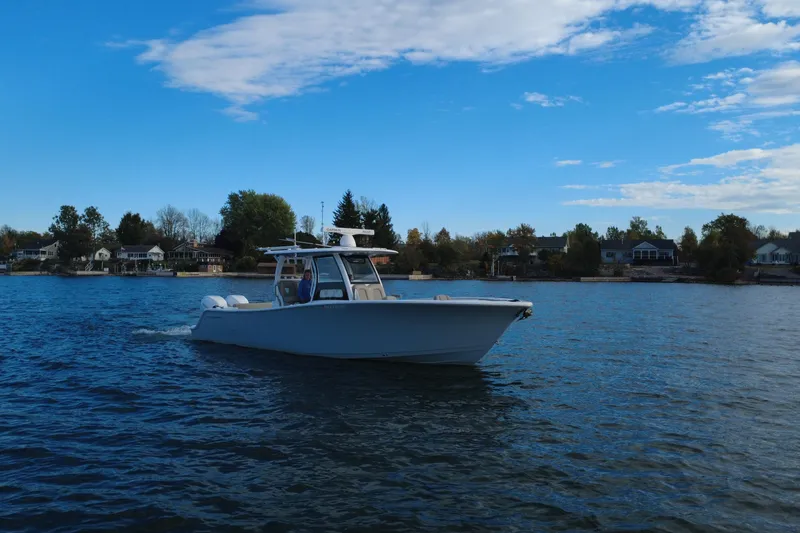 Slide: The Image of 2022 Sportsman Open 322 Center Console boat cruising on a scenic lake. - 3