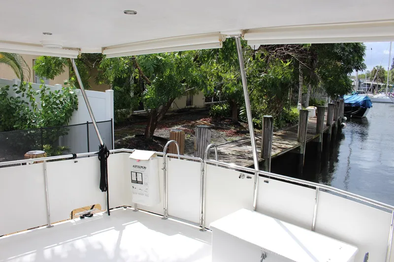 Slide: The Image of Rear deck view of a 2007 Jefferson 45 Motor Yacht docked by a lush, green shoreline. - 4