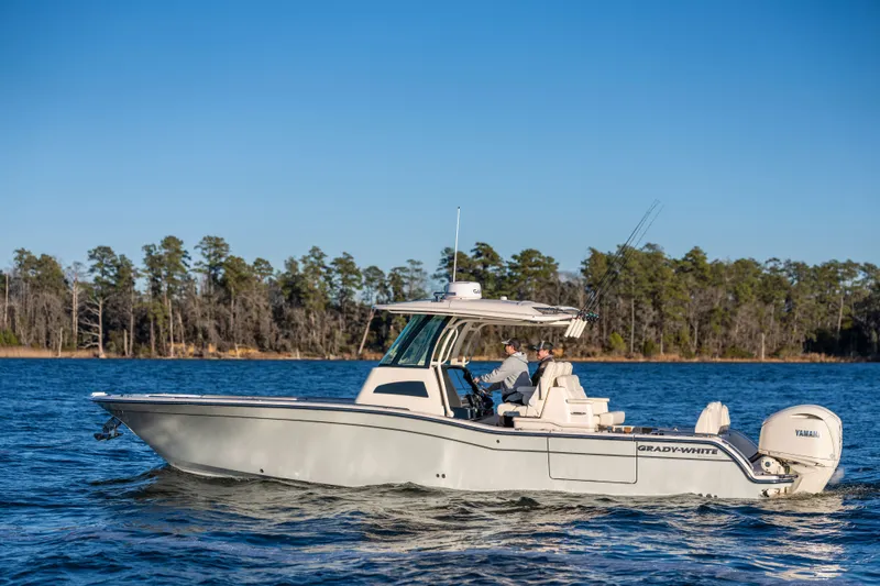 Slide: The Image of A 2027 Grady-White 321 CE boat cruising on calm waters with a wooded shoreline in the background. - 1