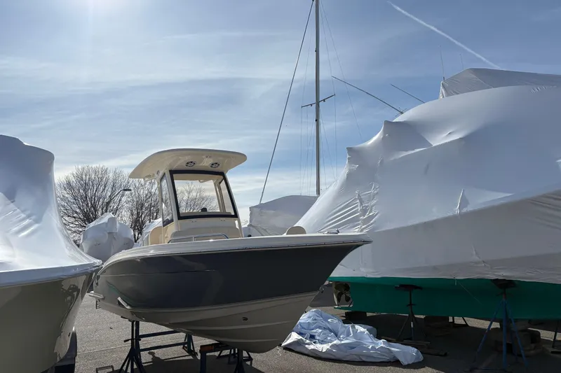 Slide: The Image of 2026 Scout 220 XSF boat on display, surrounded by covered vessels under a clear sky. - 2