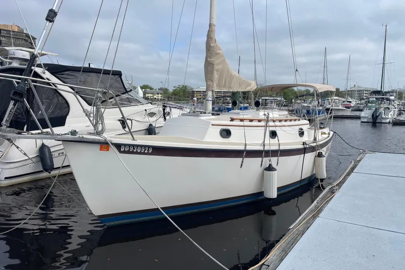 Slide: The Image of 1987 Com-Pac 27 sailboat docked at marina, featuring classic design and white hull. - 1