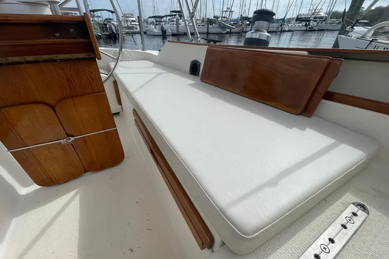 Slide: The Image of 1987 Com-Pac 27 sailboat cockpit with white seating and wooden accents at marina. - 11