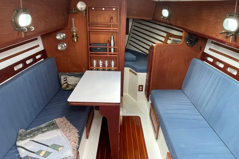 Slide: The Image of Interior of a 1987 Com-Pac 27 sailboat with blue seating and wooden accents. - 13