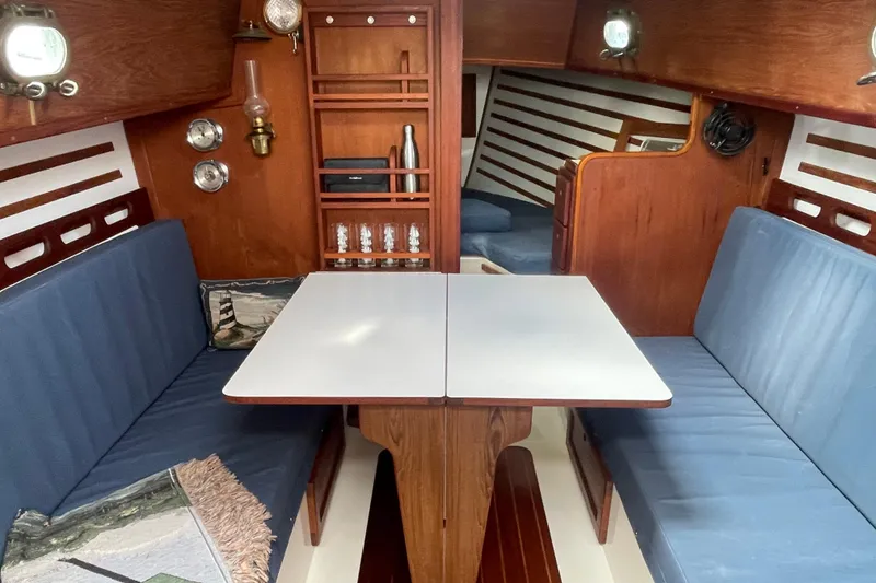 Slide: The Image of Interior of 1987 Com-Pac 27 sailboat with wooden finish and blue seating. - 14