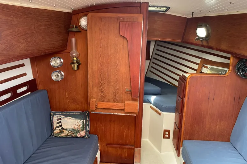 Slide: The Image of Interior of a 1987 Com-Pac 27 sailboat with wooden finishes and blue cushions. - 15