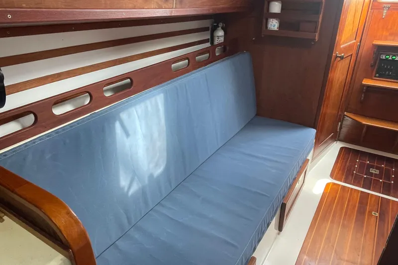 Slide: The Image of Interior of 1987 Com-Pac 27 sailboat with blue cushioned seating and wooden accents. - 16