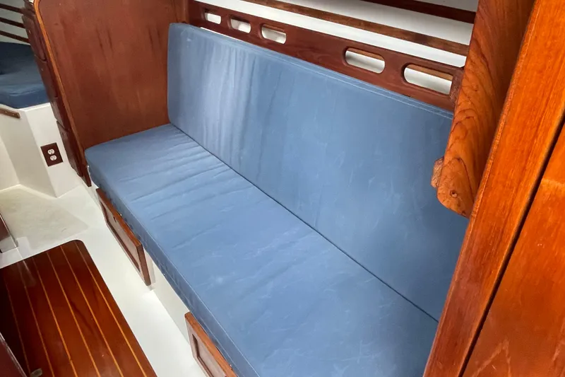 Slide: The Image of Interior of 1987 Com-Pac 27 sailboat with blue cushioned seating and wooden accents. - 17