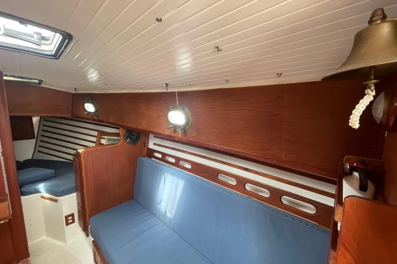Slide: The Image of Interior of 1987 Com-Pac 27 sailboat with wooden paneling and blue seating. - 18