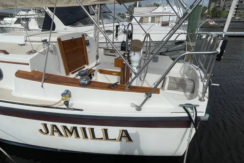 Slide: The Image of 1987 Com-Pac 27 sailboat "Jamilla" docked, showcasing cockpit and deck details. - 2
