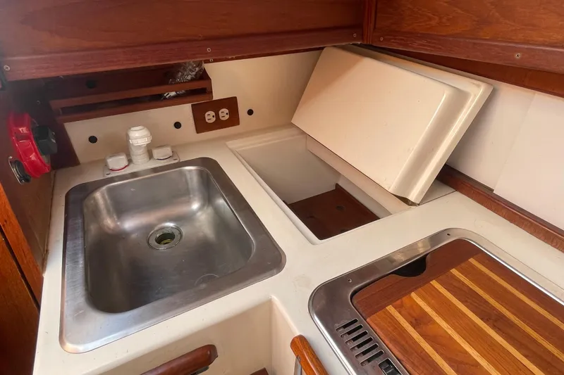 Slide: The Image of Compact kitchen area in a 1987 Com-Pac 27 sailboat with sink and wooden countertop. - 20