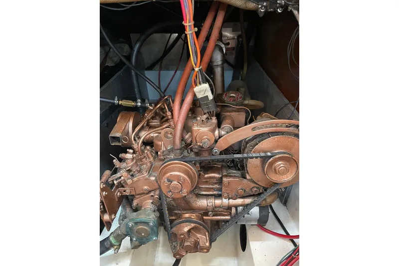 Slide: The Image of Engine of a 1987 Com-Pac 27 sailboat with visible belts and wiring. - 25
