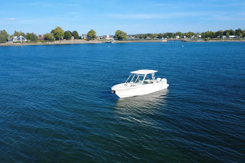 Slide: The Image of 2025 Sailfish 276 DC boat on calm blue water near a scenic shoreline. - 2
