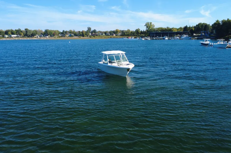 Slide: The Image of 2025 Sailfish 276 DC boat cruising on a serene lake under a clear blue sky. - 3