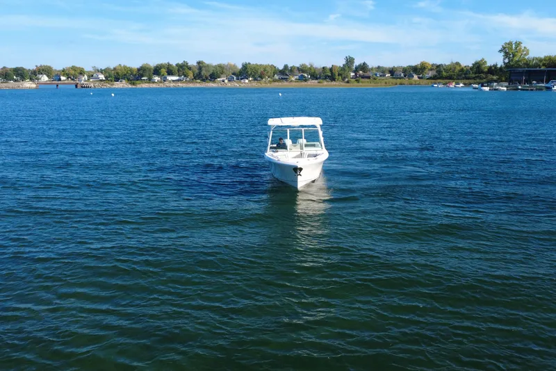Slide: The Image of 2025 Sailfish 276 DC boat cruising on a serene lake under a clear blue sky. - 4