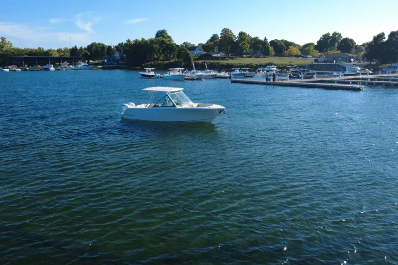 Slide: The Image of 2025 Sailfish 276 DC boat on calm blue water near a marina. - 5