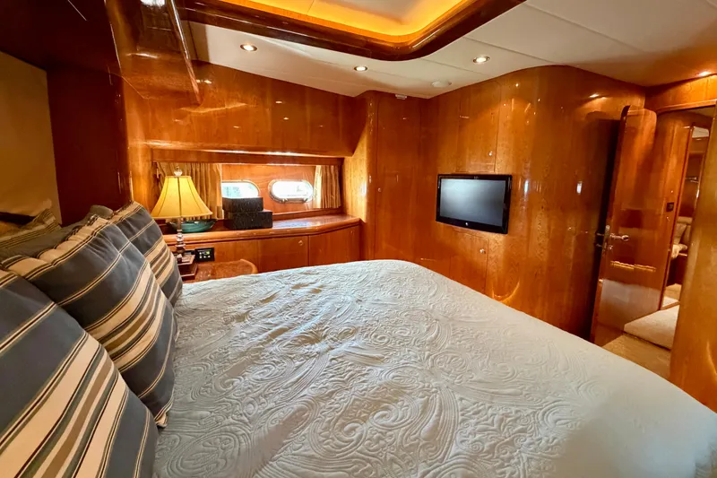 Slide: The Image of Luxurious yacht bedroom with wood paneling, striped pillows, and a mounted TV. Horizon 92 model. - 86