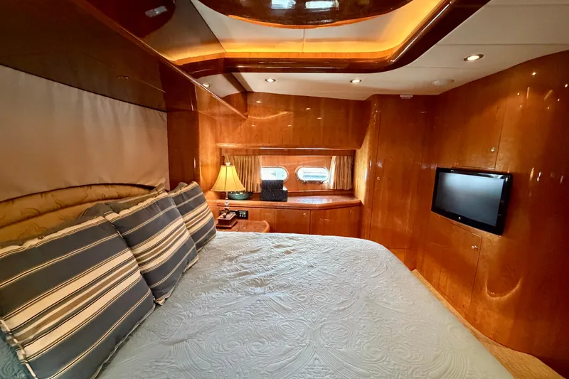 Slide: The Image of Luxurious yacht bedroom with wood paneling, striped pillows, and a mounted TV. Horizon 92 model. - 87