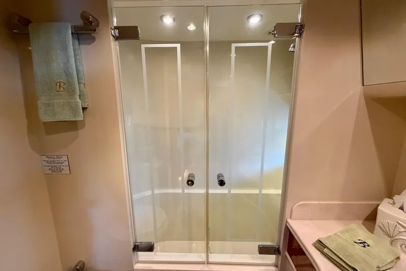 Slide: The Image of Glass shower doors in a Horizon 92 yacht bathroom with green towels. - 92