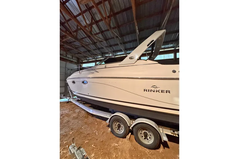 The Image of 2007 Rinker 270 Express Cruiser boat on trailer in a covered storage area. - 0