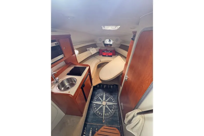 Slide: The Image of 2007 Rinker 270 Express Cruiser cabin interior with kitchenette and seating area. - 13