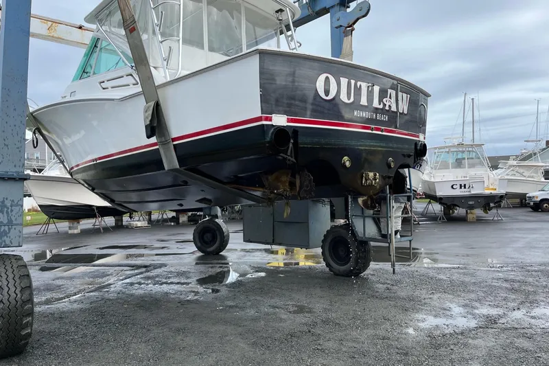 Slide: The Image of 2012 Cabo 32 Express boat lifted in a marina, labeled "Outlaw." - 14
