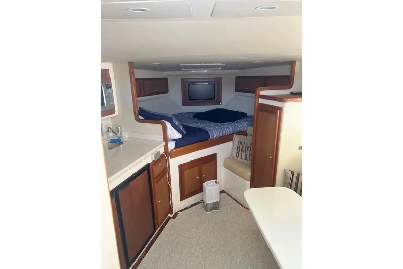 Slide: The Image of Interior of 2012 Cabo 32 Express boat with cozy bed, kitchenette, and wooden cabinetry. - 23