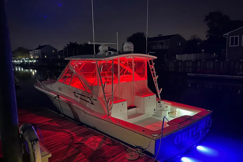 Slide: The Image of 2012 Cabo 32 Express boat docked at night with vibrant red and blue lighting. - 6