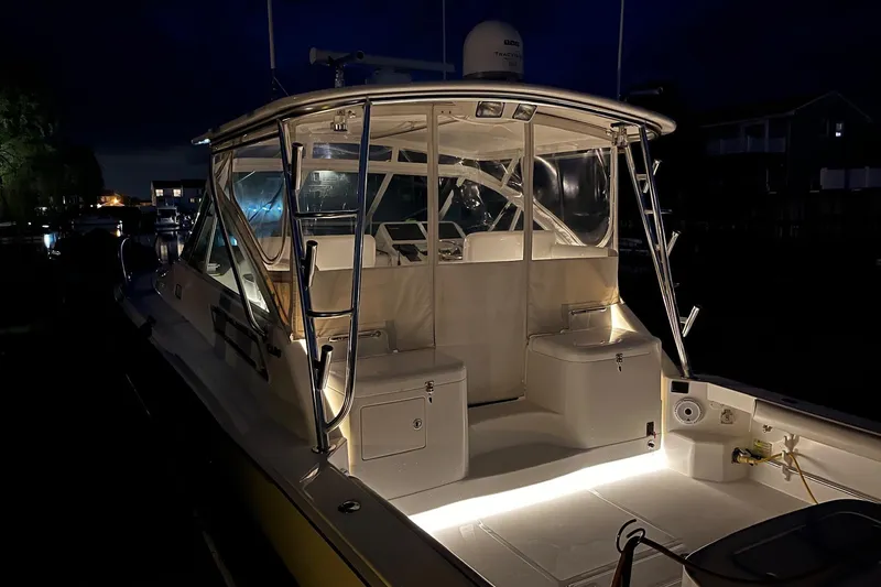 Slide: The Image of 2012 Cabo 32 Express boat illuminated at night, showcasing cockpit and seating area. - 7