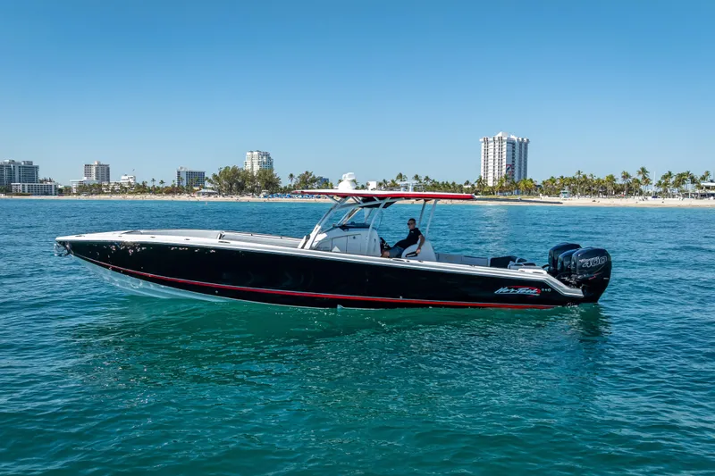 Slide: The Image of 2018 Nor-Tech 390 Sport Center Console boat cruising near a coastal city skyline. - 22