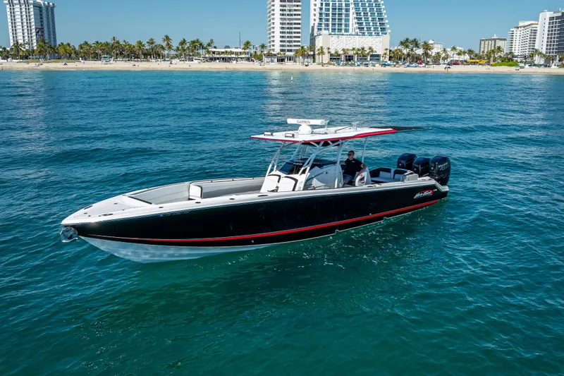 Slide: The Image of 2018 Nor-Tech 390 Sport Center Console boat cruising near a coastal city skyline. - 24