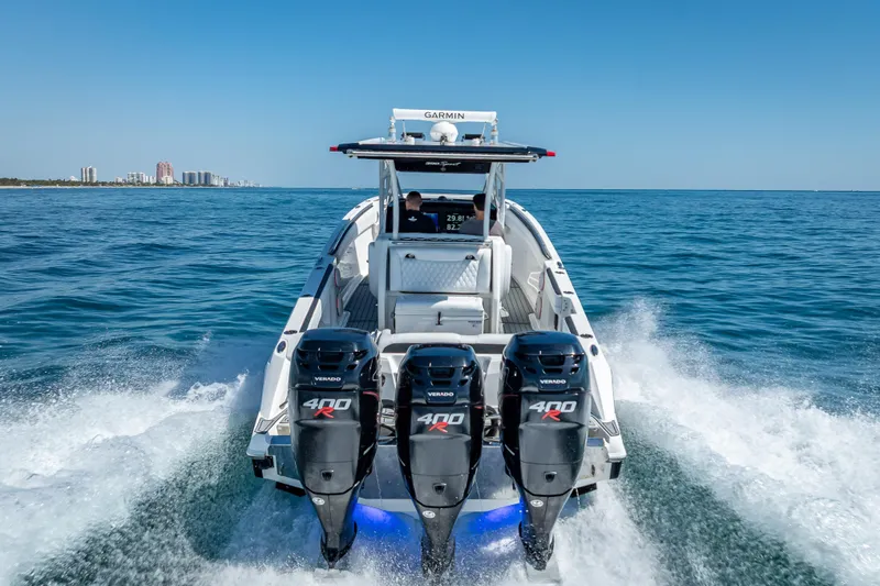 Slide: The Image of 2018 Nor-Tech 390 Sport Center Console cruising on open water with triple outboard engines. - 27
