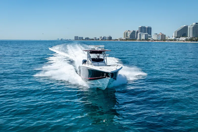 Slide: The Image of 2018 Nor-Tech 390 Sport Center Console cruising on blue ocean near city skyline. - 32