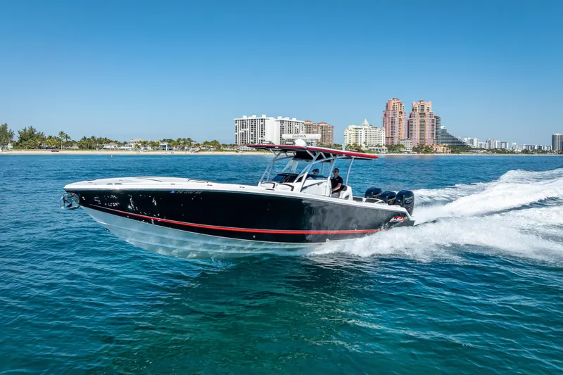 Slide: The Image of 2018 Nor-Tech 390 Sport Center Console cruising on blue ocean near city skyline. - 33