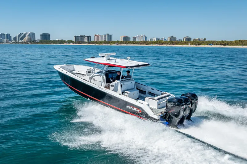 Slide: The Image of 2018 Nor-Tech 390 Sport Center Console cruising on blue ocean near city skyline. - 35