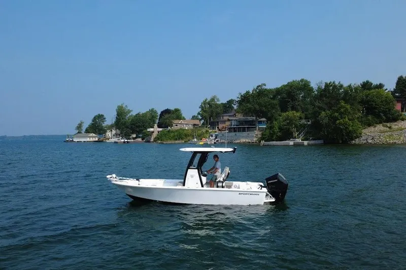 The Image of 2025 Sportsman Masters 227 Bay Boat cruising on a scenic lake near shoreline homes. - 0