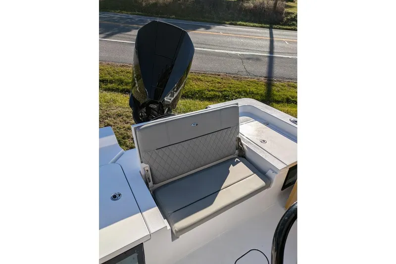 Slide: The Image of 2025 Sportsman Masters 227 Bay Boat with cushioned seating and outboard motor. - 12