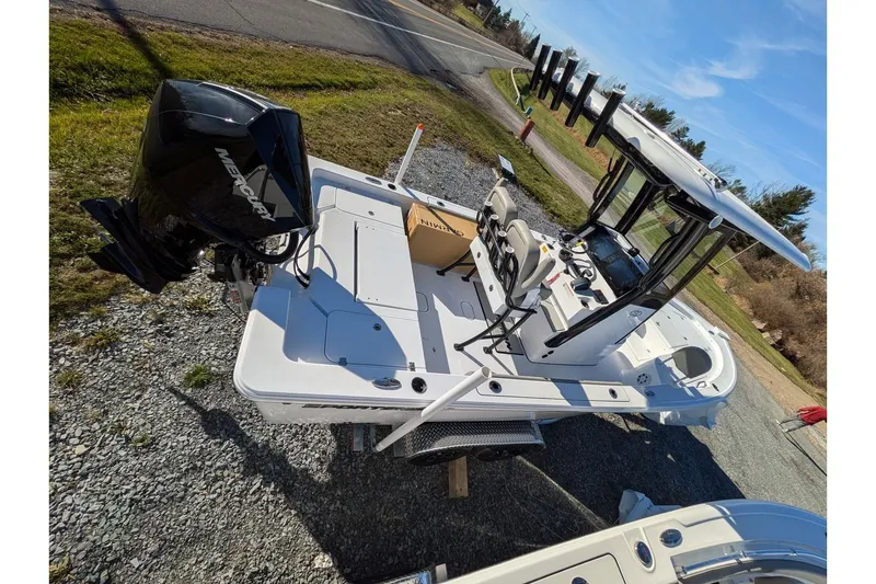 Slide: The Image of 2025 Sportsman Masters 227 Bay Boat with Mercury engine, parked on gravel. - 14