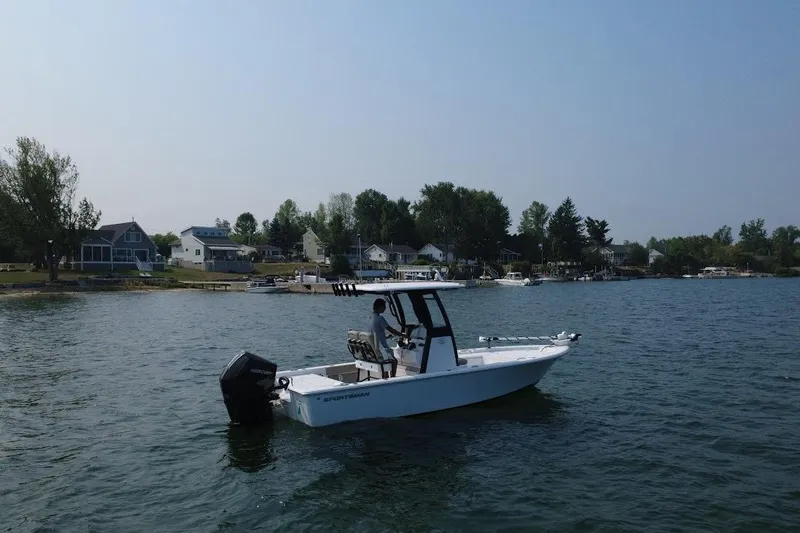 Slide: The Image of 2025 Sportsman Masters 227 Bay Boat on a serene lake near waterfront homes. - 2