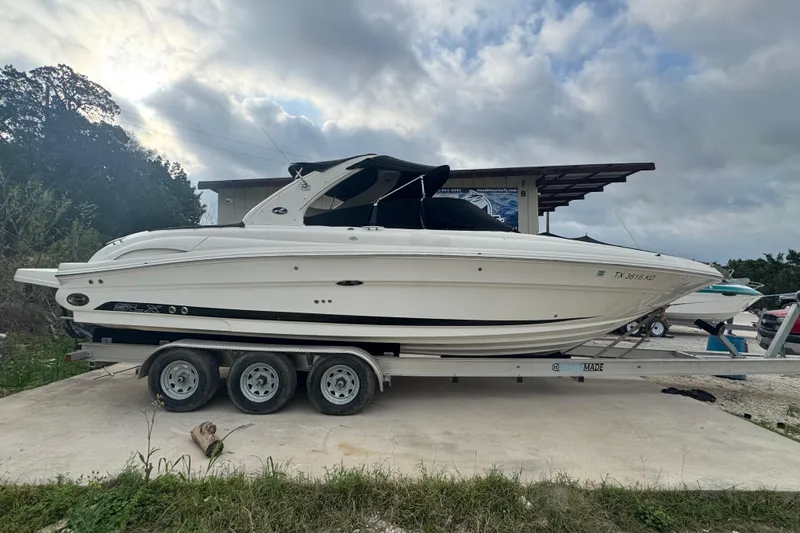 The Image of 2005 Sea Ray 290 SLX boat on a trailer under cloudy skies. - 0